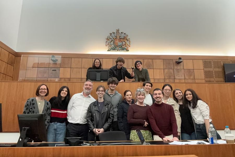 Students and tutors of the Personal Construct Psychology and Counselling programme standing together in the courtroom at the University of Hertfordshire